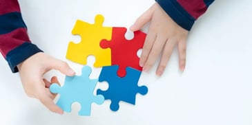 Mãos infantis montando um quebra-cabeça colorido. Conceito de autismo.