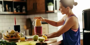Mulher preparando suco de frutas na cozinha de casa. Conceito de mindful eating.